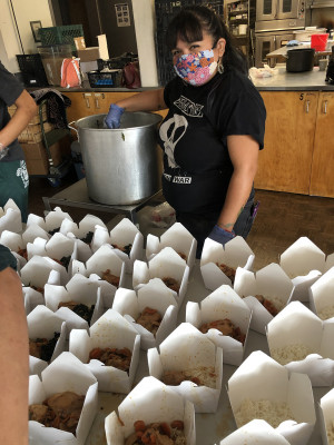 person in mask filling take out containers with food