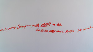 Red text hand drawn on white walls. Excerpt: Letters from a parrallel reality